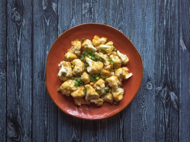 Turuncu bir tabakta kızarmış karnabahar parçaları.. 