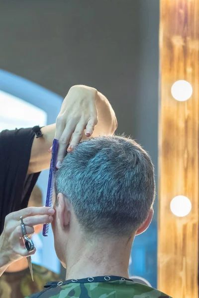 Mann im Friseurstuhl, Friseur frisiert sich die Haare. — Stockfoto