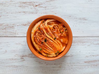 Ahşap arka plan üzerinde bir kase kimchi lahana