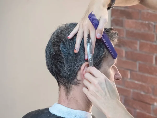 Mann im Friseurstuhl, Friseur frisiert sich die Haare. — Stockfoto