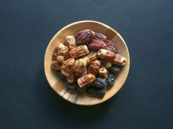 Dates in a wooden bowl on a black background. — Stock Photo, Image