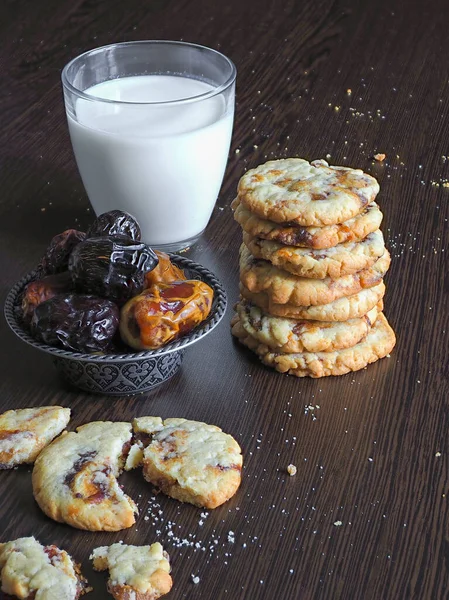 Čerstvé šťavnaté datlové sušenky s mlékem na tmavém dřevěném povrchu — Stock fotografie