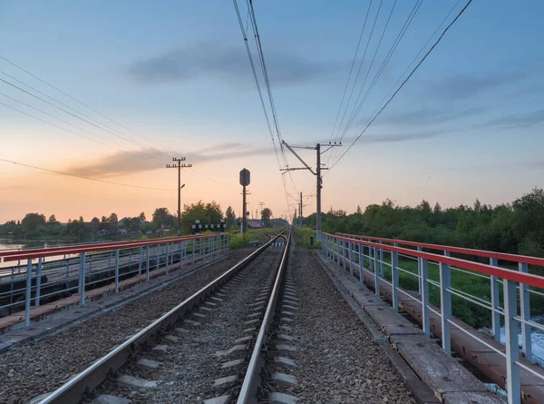 Railroad tracks on the bridge by the countryside in the evening — Stock Photo, Image