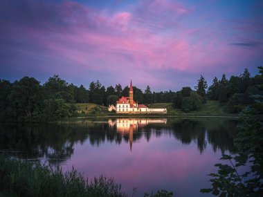 Gün batımında güneş ışığı altında renkli bulutlarla ünlü manastır sarayı. Gatchina, Rusya 'daki Peri Masalı Şatosu. Popüler fotoğraf mekanları. Seyahatler, kartpostallar için fikirler