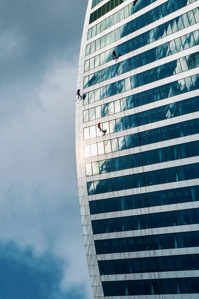 Trabajadores de gran altura lavan ventanas en la parte superior de un edificio de vidrio y hormigón — Foto de Stock