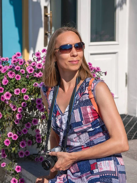 Retrato de estilo de vida brilhante de mulher bonita sorridente sentado em parapeito com flores. Menina elegante na moda relaxante. Viagens e conceito de estilo de vida ativo — Fotografia de Stock