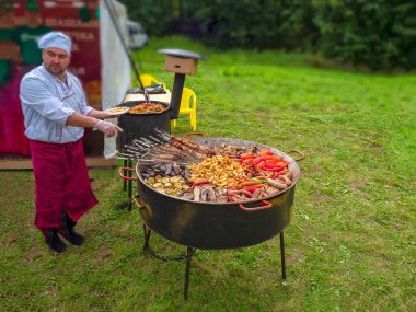 - Rusya. 5 Eylül 2020. Aşçı doğadaki bir pikniğe işaret ediyor. Büyük et barbeküsü, yol kenarındaki kafe..