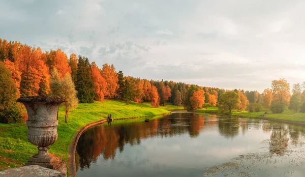 Panorama del parque otoñal. Hermoso paisaje otoñal con jarrón de piedra vintage y árboles rojos junto al lago. Pavlovsk. —  Fotos de Stock
