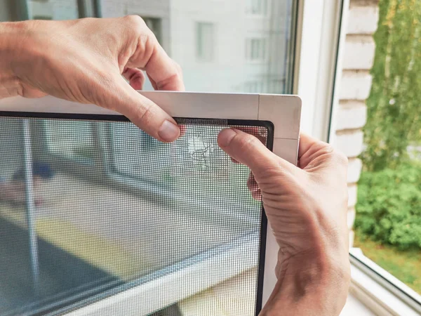 Net holes. Fix holes in mosquito screen. Broken mosquito screen. Repair process. Close up. 