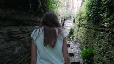 Genç kadın dağlarda dar bir yarık içine tırmanma