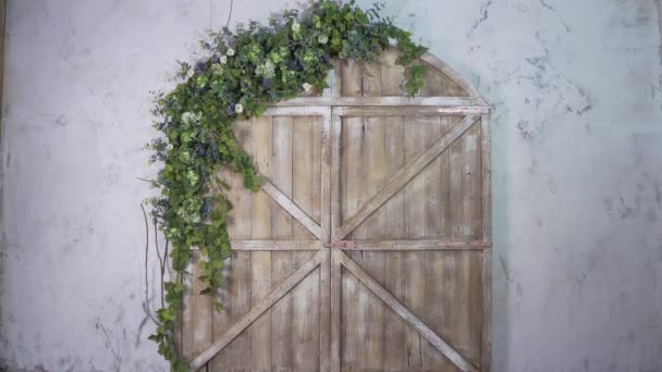 Young woman moves vintage stepladder on the background of beautiful gate with flowers — Stock Video