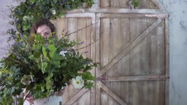 A florista menina segura um vaso de flores em suas mãos e move-la para cima e para baixo, escondendo seu rosto — Vídeo de Stock