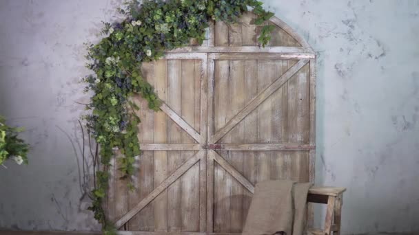 Linda menina decoradora carrega um vaso de flores e coloca em uma pequena escadaria vintage contra uma bela fotozona — Vídeo de Stock