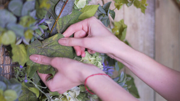 Hands of the girl close-up: decorating flowers with a branch of green eucalyptus