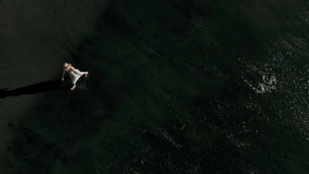Вид с воздуха на девушку на черном пляже, камера вращается, Лос Гигантес, Тенерифе, Канарские острова, Испания — стоковое видео
