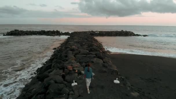 Het meisje gaat langs de pier in een kleine baai bij zonsondergang, luchtfoto — Stockvideo