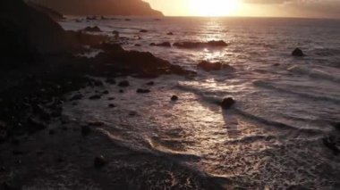 Tenerife, büyük taşlar ve siyah kum ile bir plaj kuzey kıyısında Fantastik güzel gün batımı. Yukarıdan görüntüle.