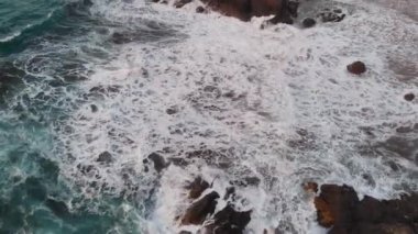 Hava. Tenerife adasının kuzey kıyısında en iyi görünümü, plaj Benijo. Gün batımında okyanusta izole kayalara ve volkanik kum plajına çöken dalgalar