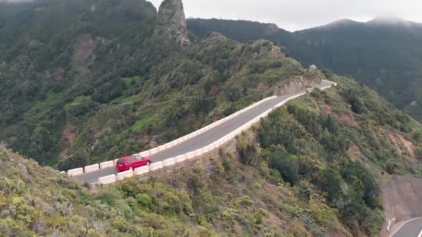 Aero View-samotny samochód jeździ przez wąską i niebezpieczną drogę wysoko w zielonych górach. Serpentine na dużej wysokości, Park Narodowy Anaga, Teneryfa — Wideo stockowe