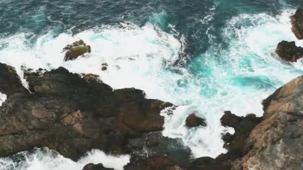 海の波とテネリフェ島の美しい岩の海岸の航空写真。海に到達し、凍った溶岩から出てくる大きな岩に対して危険な波が衝突する — ストック動画