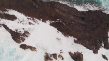 Donmuş lavlardan kaynaklanan büyük kayalar. Tenerife kıyılarında kuş bakışı, kristal berraklığında okyanus ve köpük. Drone'dan ateş