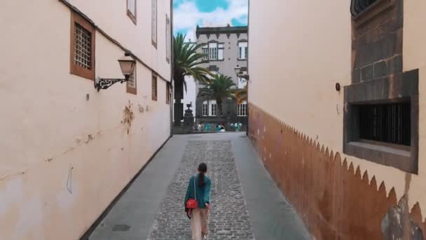Las Palmas de Gran Canaria, Spanien - 23. April 2019: Luftaufnahme - junges stilvolles Mädchen spaziert durch eine enge Straße der alten spanischen Stadt, von oben gesehen. — Stockvideo