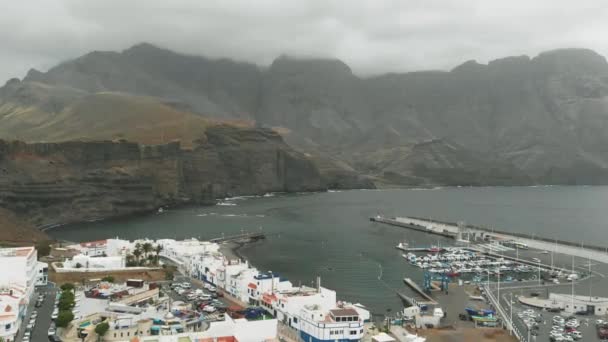 Bay for yachts off the coast of the Atlantic Ocean on an overcast day - aerial view. Massive mountains of high altitude on the background. Agaete, Gran Canaria — Stock Video