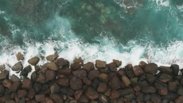 Zobrazení shora dolů. Stavba kamenů k posílení a ochraně pobřeží od oceánu-pohled na ptačí oko. Velké kameny a oceán tyrkysové barvy. — Stock video