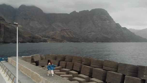 Een vrouw loopt langs gigantische betonnen bescherming stenen van een vogel eye view. Agaete, Gran Canaria — Stockvideo