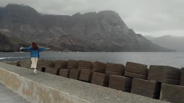 Drone synvinkel-glad ung flicka hoppar och ha kul på bakgrunden av Atlanten och vackra berg. Agaete, Gran Canaria, Spanien — Stockvideo