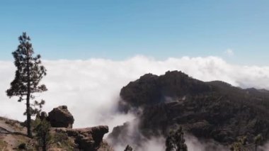 Drone uçuş dağların üzerinde güneşli bir günde, bulutların üstünde, Gorge üzerinden, Pico de las Nieves, Gran Canaria