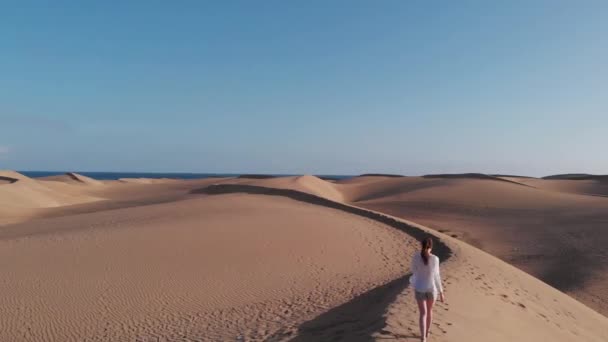 Tournage cinématographique - une jeune fille en balades blanches le long du bord d'une dune dans le désert, sur les rives de l'océan Atlantique, Maspalomes aériens, Gran Canaria 