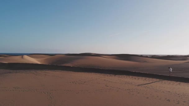 Statische Luftaufnahme - ein attraktives Mädchen geht am Sand entlang in den Strahlen der untergehenden Sonne, Maspalomas, Gran Canaria — Stockvideo