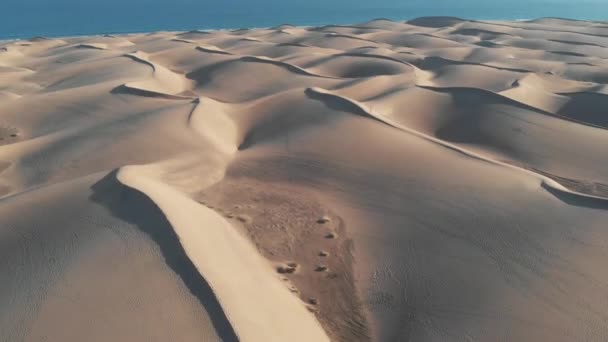 AEREALE. Volo cinematografico sul deserto al tramonto: le cime delle dune di sabbia proiettano ombre. Panorama delle attrazioni naturali della Spagna - Maspalomas, Gran Canaria — Video Stock