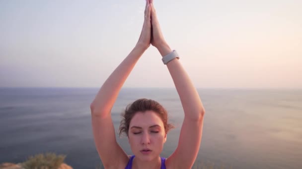 Primer plano de una chica caucásica practicando yoga. Mujer deja caer sus manos, suspira y mira a la cámara . — Vídeo de stock