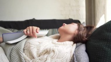Lagom ya da Hygge. Close-up - güneşli bir günde uyuyan elinde bir kitap ile bir kazak kız.