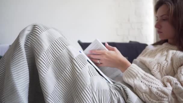 Herfst comfort-een vrouw verpakt zichzelf in een Plaid en is op zoek naar de juiste pagina in het boek — Stockvideo