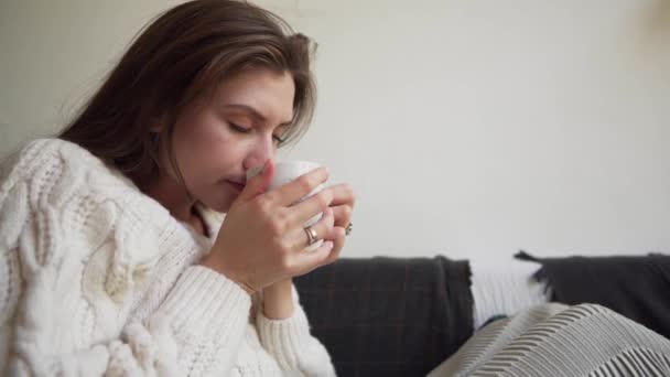 Hygge of Lagom concept. Gelukkige vrouw die een warm drankje drinkt uit een witte beker close-up. — Stockvideo