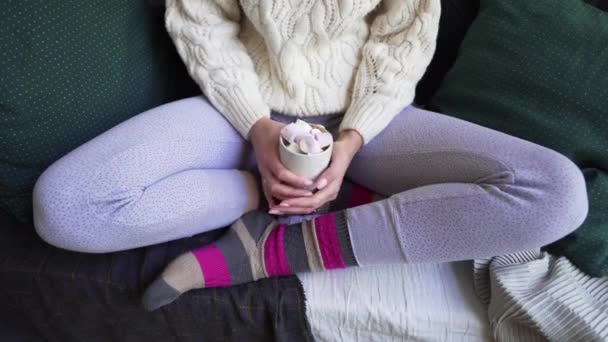 Concepto Lagom o Hygge. Una mujer con hermosos calcetines cálidos multicolores y pantalones de pijama sostiene una taza de café caliente en sus manos . — Vídeos de Stock
