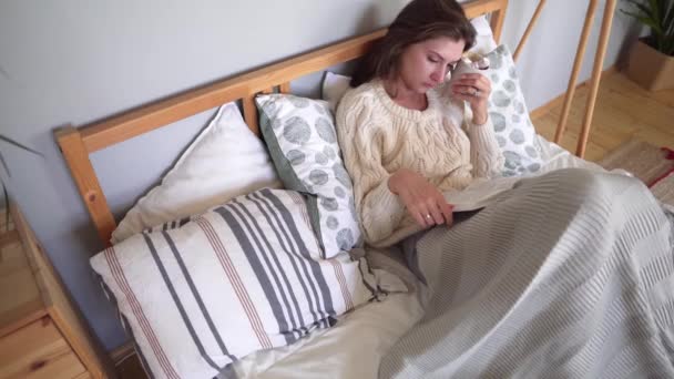 Coziness, lycka och komfort i sovrummet-flickan i sängen läser en bok och vilar efter en hård dag på en kall dag — Stockvideo