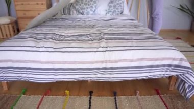 Ev elbiseli bir kız sabah erkenden yatağı yapar. Lagom kavramı