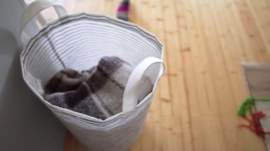 Genç bir kadın ahşap zemin arka plan üzerinde, bir çamaşır sepeti bir yünlü örme battaniye çeker