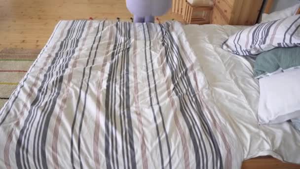Hyugge concept - beautiful girl jumping on the bed and laying down on a cozy blanket — Stock Video