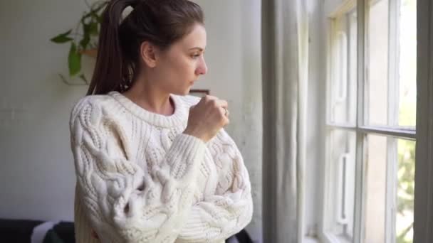 Malattia e stagione influenzale - Bella giovane donna caucasica in un maglione bianco starnutisce e strofina un naso rosso — Video Stock
