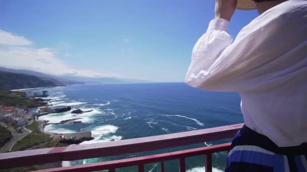 Hermosa chica con un sombrero elegante en el borde de un acantilado que mira al Océano Atlántico. Islas Canarias, España — Vídeos de Stock