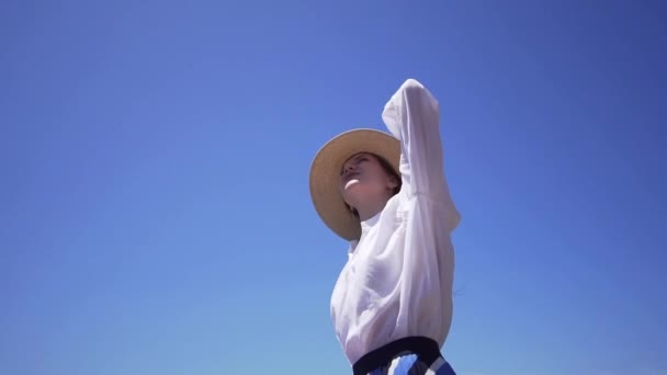 Una hermosa joven con un hermoso sombrero mira hacia arriba y alrededor. Éxito y logro . — Vídeos de Stock