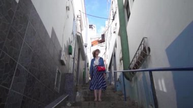 Güzel bir kadın İspanyol evleri arasında dar bir sokakta duruyor. Okyanus kıyısında renkli bir Avrupa şehrinin sokakta Turist