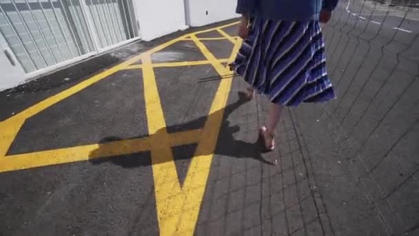 Een stijlvol meisje gaat naast een wegreparatie en gele markeringen op een warme zomerdag. Wandeling op het eiland Tenerife, Spanje — Stockvideo