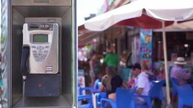 Kalabalık bir sokak arka planı ndaki eski telefon kulübesi. Turist telefon kulübesi, modası geçmiş teknoloji