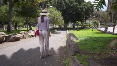 Şık kız turist güzel bir İspanyol parkta yürüyor. Tatilde yalnız bir kadın. Tenerife, İspanya